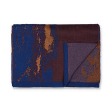 Load image into Gallery viewer, Flatlay of a knit scarf in blue and brown with gold and copper details. The background is white.
