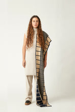 Load image into Gallery viewer, Wide shot of a young woman with a knitted scarf draped over her shoulder. She&#39;s wearing a neutral light beige outfit and black shoes. The knit scarf has an abstract pattern in dark blue and peach.
